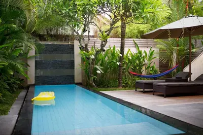 a swimming pool with a hammock in a backyard at Bali Island Villas and Spa Seminyak in Seminyak