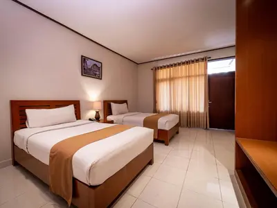 a hotel room with two beds and a television at Yulia Beach Inn Kuta in Kuta
