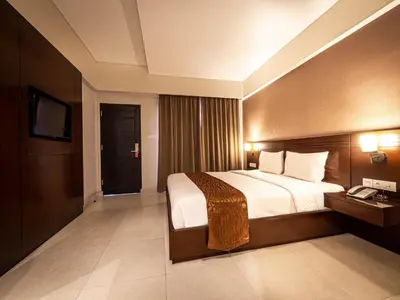 a hotel room with a bed and a television at Yulia Beach Inn Kuta in Kuta