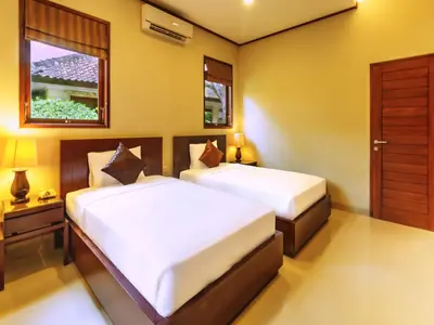 a bedroom with two beds and a window at Yulia Beach Inn Kuta in Kuta