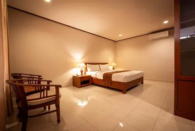 a bedroom with a bed and a chair at Yulia Beach Inn Kuta in Kuta