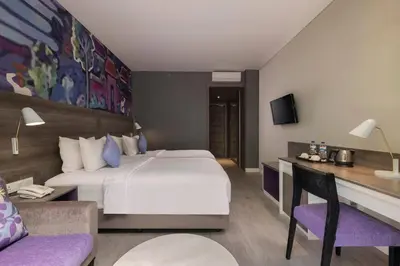 a hotel room with a large bed and a couch at Wyndham Garden Kuta Beach Bali in Kuta