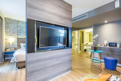 a hotel room with a large tv and a bedroom at Wyndham Garden Kuta Beach Bali in Kuta