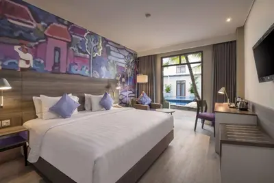 a bedroom with a large white bed and a large painting at Wyndham Garden Kuta Beach Bali in Kuta
