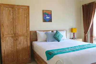 a bedroom with a large bed with a wooden door at CR Tris Rooms Seminyak in Seminyak