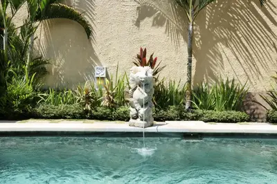 a statue sitting next to a swimming pool at The Sanyas Suite Bali in Seminyak