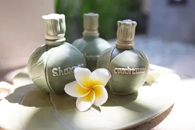 three bottles of soap with a flower on a plate at The Sanyas Suite Bali in Seminyak