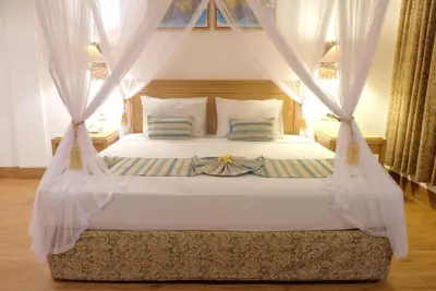 a bedroom with a white bed with curtains at Seminyak Paradiso Hotel in Seminyak