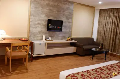 a hotel room with a desk and a tv on the wall at Seminyak Paradiso Hotel in Seminyak