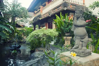 a statue in front of a garden with a pond at Seminyak Paradiso Hotel in Seminyak