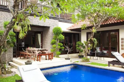 a pool in front of a house with chairs and a table at Sindhu Mertha Suite in Sanur