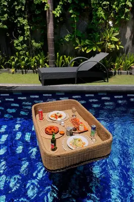 a picnic table in a swimming pool with food on it at Singgah Villas Seminyak in Seminyak