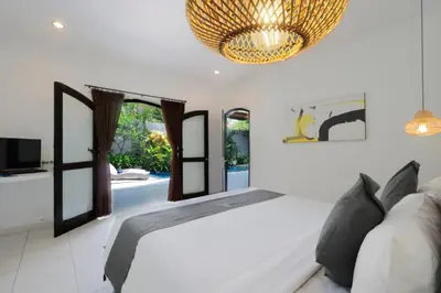 a bedroom with a bed and a chandelier at Singgah Villas Seminyak in Seminyak