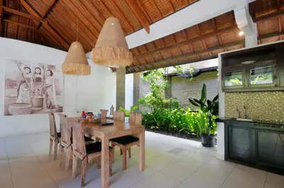 a dining room with a wooden table and chairs at Singgah Villas Seminyak in Seminyak
