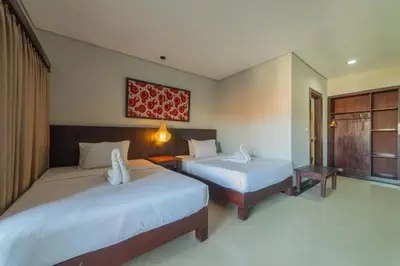 a hotel room with two beds and a window at Nirmala Hotel Jimbaran in Jimbaran