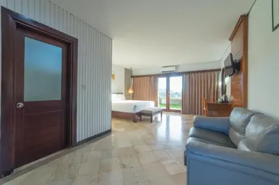a living room with a couch and a bed at Nirmala Hotel Jimbaran in Jimbaran