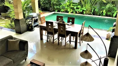 a dining area with a table and chairs next to a pool at Rumah Indah Villa in Seminyak