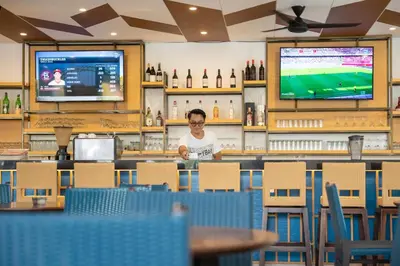 a man sitting at a bar in a restaurant at Kuta Beach Club Hotel in Kuta