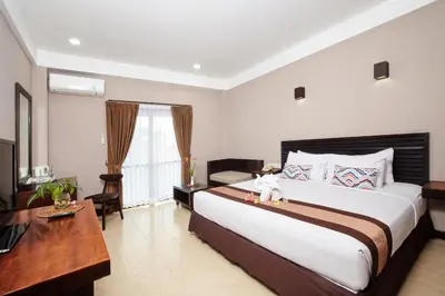 a bedroom with a large bed and a desk at Grand Santhi Hotel in Denpasar