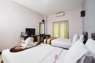 a hotel room with two beds and a television at Grand Santhi Hotel in Denpasar