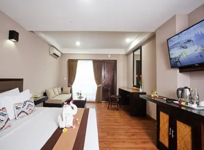 a living room with a bed and a tv at Grand Santhi Hotel in Denpasar