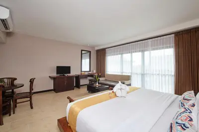 a bedroom with a large bed and a living room at Grand Santhi Hotel in Denpasar