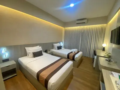 a hotel room with two beds and a sink at Grand Santhi Hotel in Denpasar