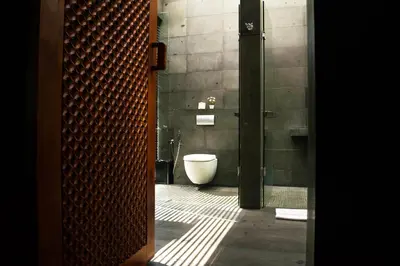 a bathroom with a toilet and a glass door at Javana Royal Villas in Seminyak