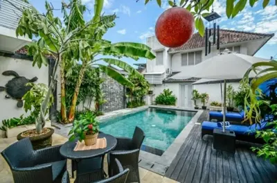 a swimming pool in a backyard with chairs and a table at Sun Shoot Villas Seminyak in Seminyak