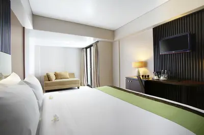 a hotel room with a large bed and a television at Hotel Santika Kuta in Kuta