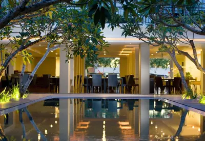 a pool in the lobby of a hotel with tables and chairs at Hotel Santika Kuta in Kuta