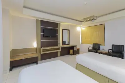 a hotel room with a bed and a flat screen tv at Urbanview Hotel Taman Suci Denpasar Bali in Denpasar