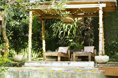 a pergola with two chairs and a table in a garden at Villa Bella Bali - Authentic Balinese Luxury Villa with Tropical Elegance - Nanny and Cook in Canggu
