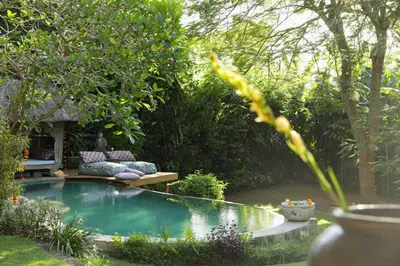 a small swimming pool in a garden with a bench at Villa Bella Bali - Authentic Balinese Luxury Villa with Tropical Elegance - Nanny and Cook in Canggu
