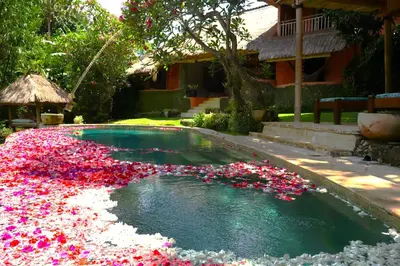 a pool full of flowers in front of a house at Villa Bella Bali - Authentic Balinese Luxury Villa with Tropical Elegance - Nanny and Cook in Canggu