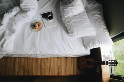 a white bed with a bowl of food and a guitar at Cara Cara Inn in Kuta