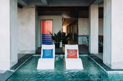 two chairs sitting in a pool of water in a building at Cara Cara Inn in Kuta