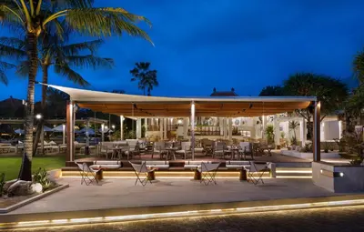 a pavilion with tables and chairs at night at Sadara Resort in Nusa Dua