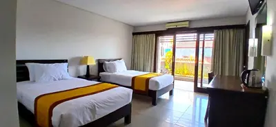a hotel room with two beds and a balcony at Nirmala Hotel & Convention Centre in Denpasar
