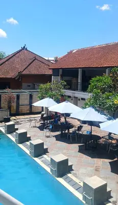 a pool with tables and chairs and umbrellas at Nirmala Hotel & Convention Centre in Denpasar
