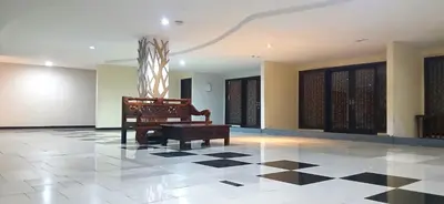 a room with a chair and a piano on a tiled floor at Nirmala Hotel & Convention Centre in Denpasar
