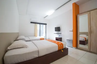 a bedroom with two beds and a mirror at Adikara Renon in Denpasar