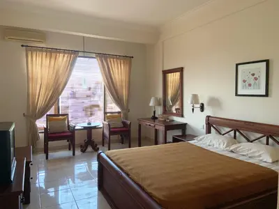 a bedroom with a bed and a desk and a window at Nirwana Suites in Denpasar