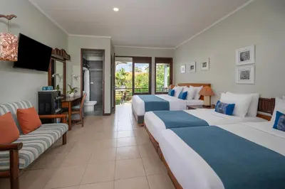 a hotel room with two beds and a couch at Pondok Sari Kuta in Kuta