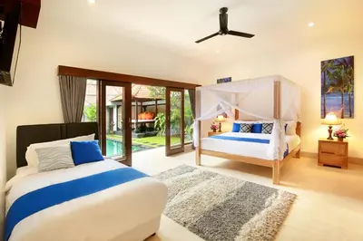 a bedroom with two beds and a ceiling fan at Concetta Villa Seminyak Beachside By Bali Asia Villa in Seminyak