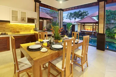 a kitchen and dining room with a wooden table and chairs at Concetta Villa Seminyak Beachside By Bali Asia Villa in Seminyak