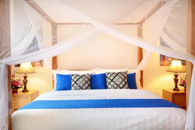 a bedroom with a blue and white bed with curtains at Concetta Villa Seminyak Beachside By Bali Asia Villa in Seminyak