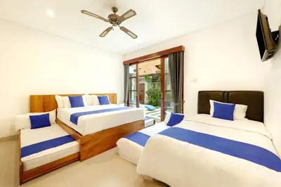 a bedroom with two beds and a ceiling fan at Lucia Villa Seminyak Beachside By Bali Asia Villa in Seminyak