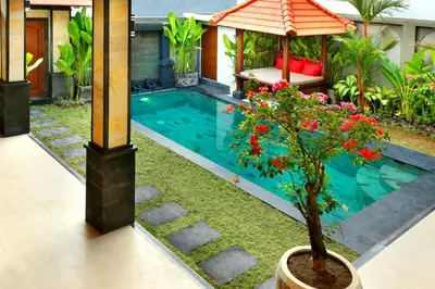 a swimming pool with a plant in a pot next to a house at De Liza Villa Seminyak Beachside By Bali Asia Villa in Seminyak