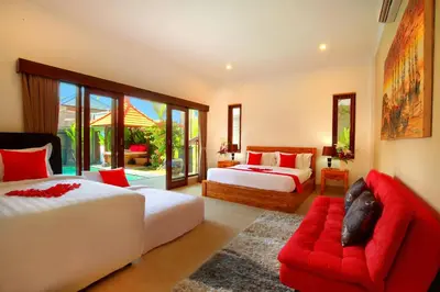 a bedroom with two beds and a red couch at De Liza Villa Seminyak Beachside By Bali Asia Villa in Seminyak